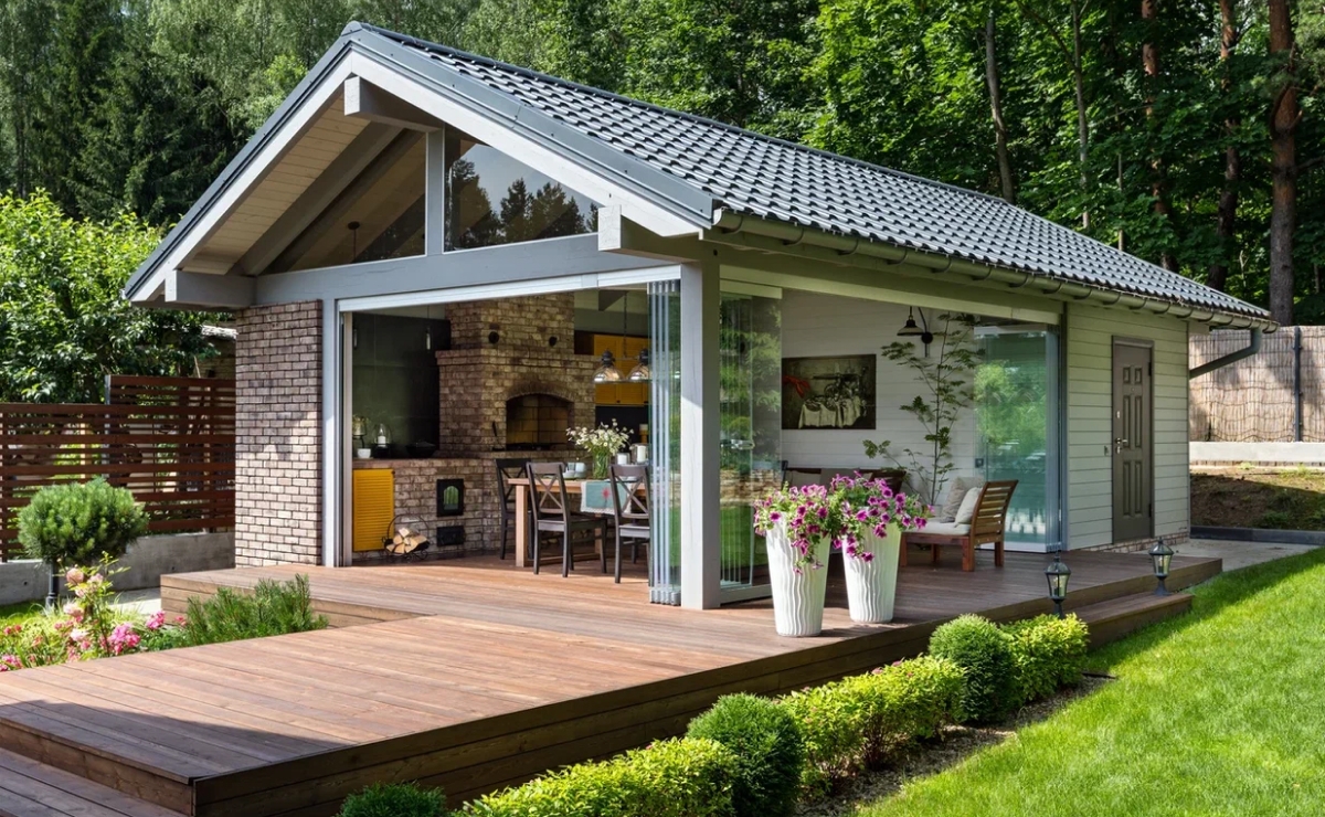 Дом выполнен в скандинавском стиле. Европейский образ дома определяет выбранная цветовая гамма отделочных материалов. Снаружи стены тонированы в светло-серый жемчужный оттенок. Для цоколя здания, подпорных стен и террасы использовали натуральный серый камень с рельефной текстурой.<br><br>

В качестве материала для кровли выбрали натуральную крупноформатную черепицу с «голландским» S-образным профилем. Такой прием напоминает изящную архитектуру античности, воплощенную в современной элегантной форме кровли цвета графит. <br><br>

Дом получился легким, светлым и достаточно просторным. Архитектура дома выразительна и логична, а внутренние объемы достаточны для того, чтобы разместить все необходимые помещения. <br>
На первом этаже расположены прихожая, лестничный холл, хозяйская спальня, ванная комната, гостиная со вторым светом, столовая и кухня. <br> 
Второй этаж отдали уже взрослым детям и гостям. В доме спроектирован и цокольный этаж. Там расположили зону отдыха с сауной. На этом этаже также предусмотрена хозяйственная комната/постирочная, душевая, санузел и зона для отдыха с сауной. <br>
Продуманная планировка и множество окон делают дом нарядным, а тонкий рисунок оконных переплетов и белые наличники подчеркивают его изящество. <br><br>

На улице спроектировали беседку с зоной барбекю, которую с домом соединяет общий настил из лиственницы. Безрамное остекление, предусмотренное в беседке, позволяют легко сделать пространство полностью открытым или, наоборот, закрыться в ветреную погоду, разжечь огонь и посидеть за семейными разговорами.
